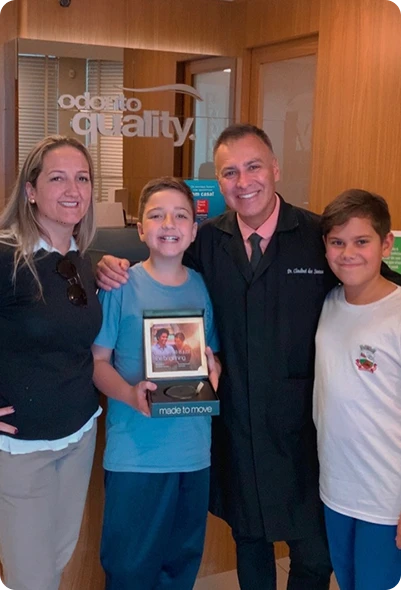Dr. Claudinei dos Santos com paciente e família durante entrega do kit Invisalign na Clínica OdontoQuality.